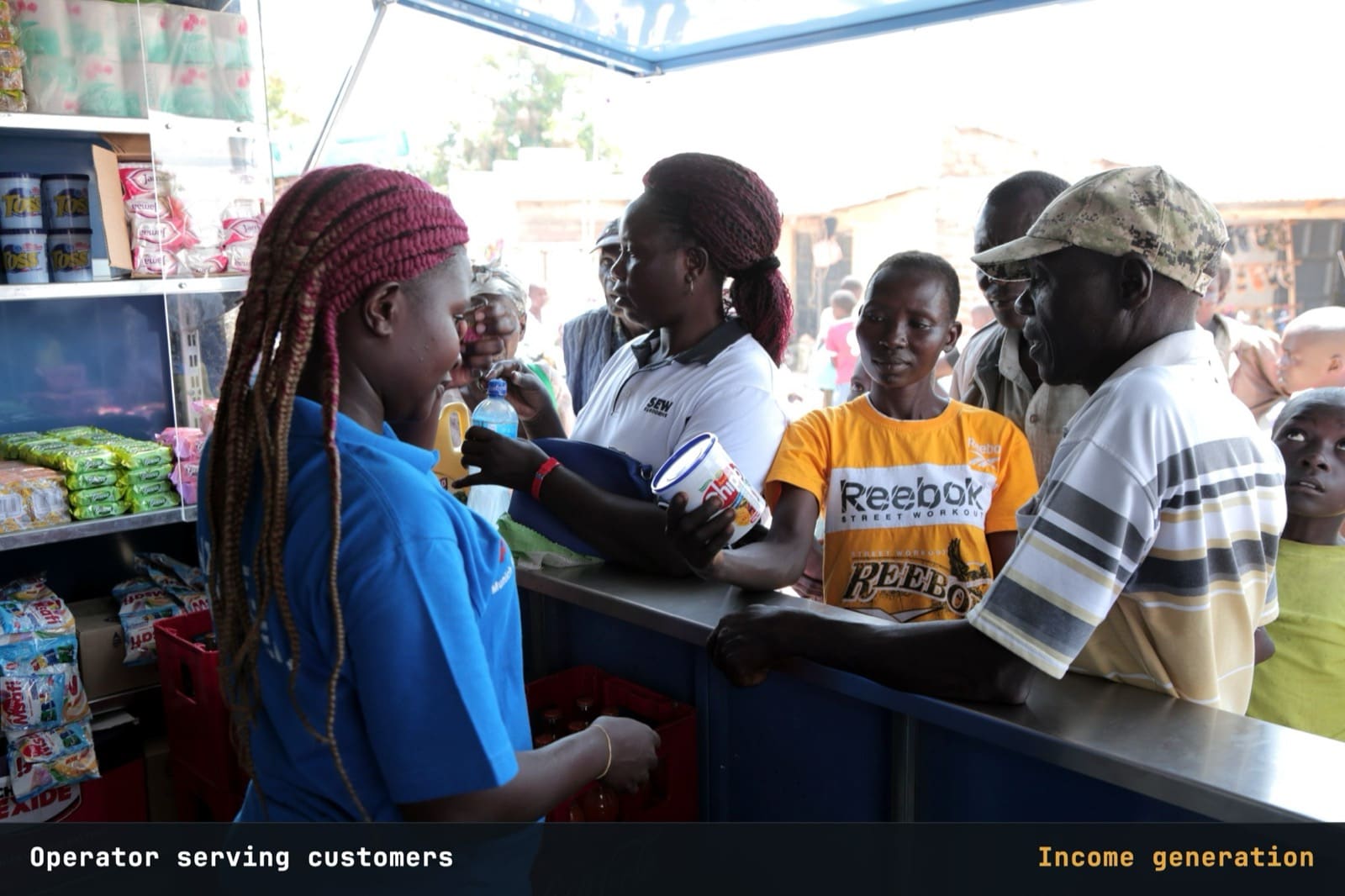 Operator behind a kiosk counter serving customers under solar-powered lights.