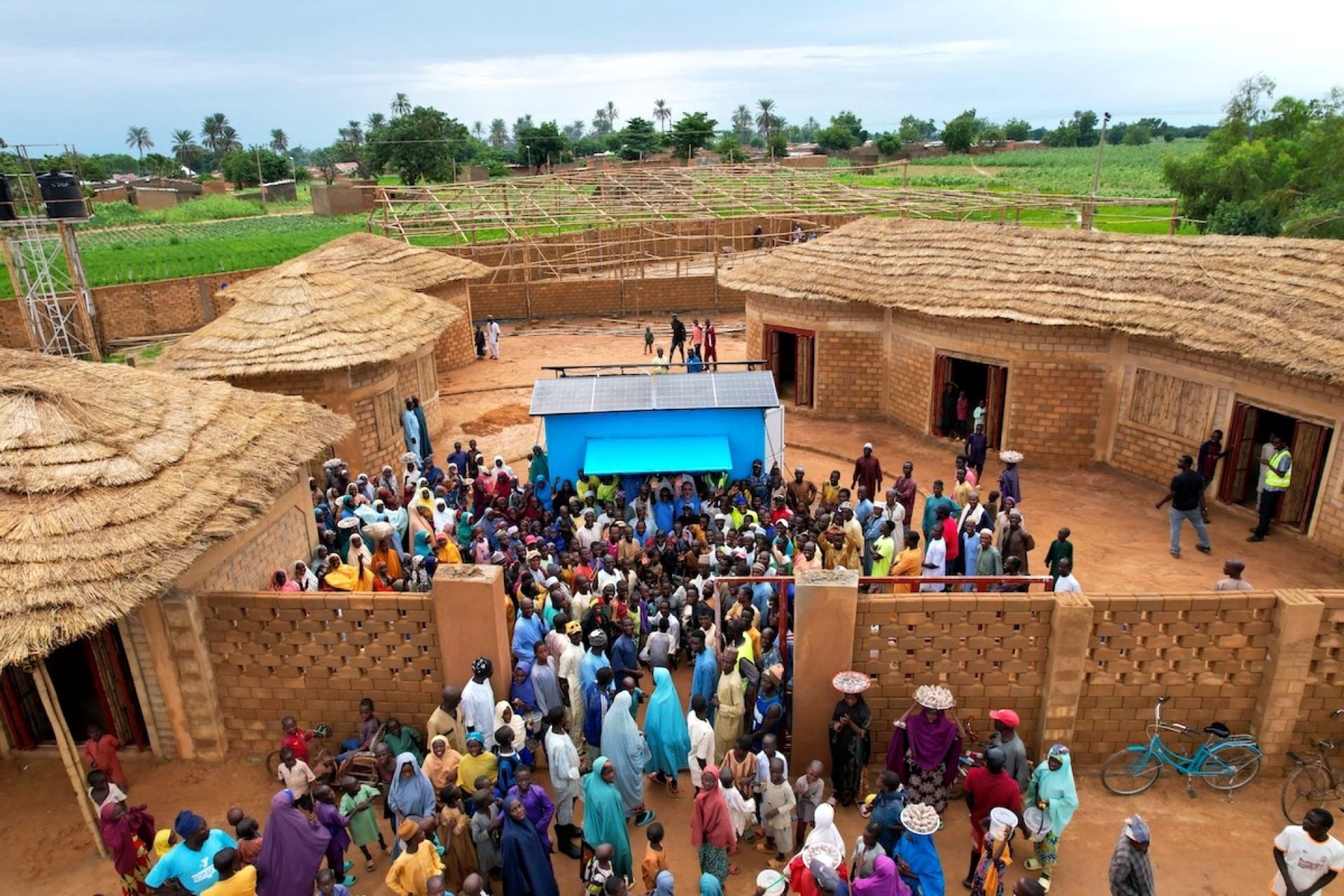 Aerial view of a completed PULSE Centre — rooftop solar, courtyard, surrounding settlement.